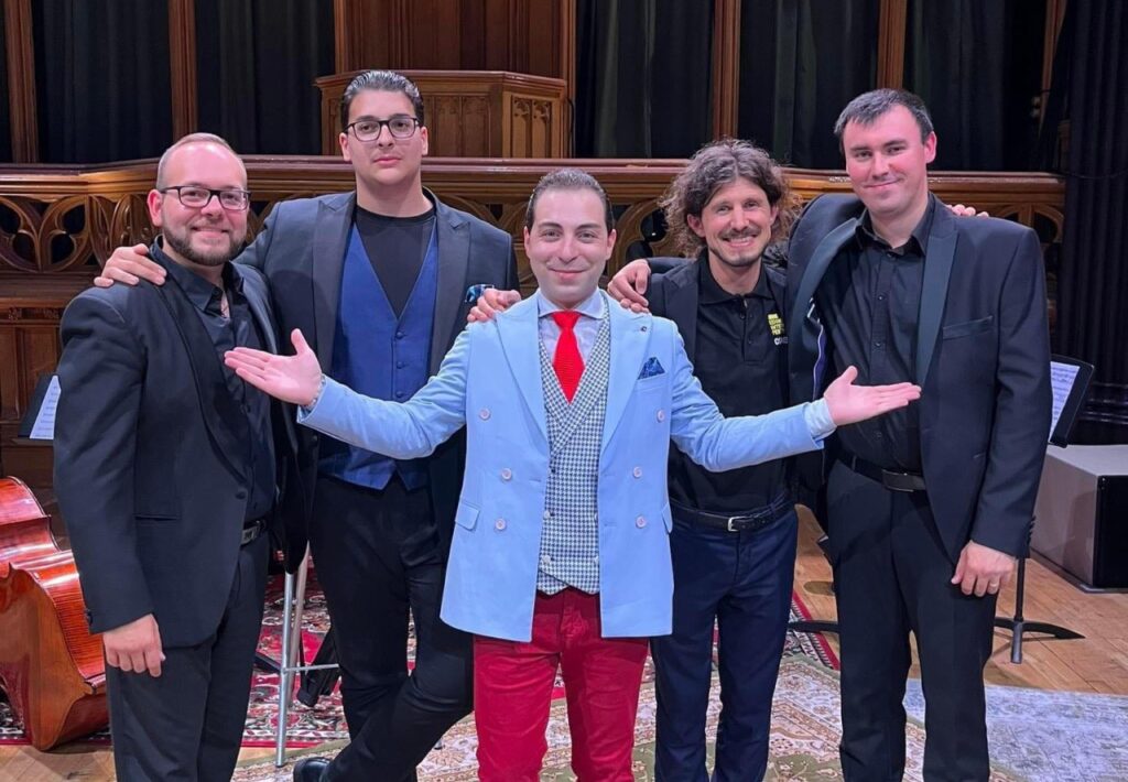 Group photo of Geza & The 5 DeViLs. The photograph shows five people, including violist Bélu Botoš, standing on the far left, and violin virtuoso Geza Hosszu-Legocky, positioned in the middle.