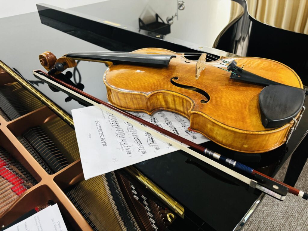 Viola, the bow and sheet notes lying on the piano.