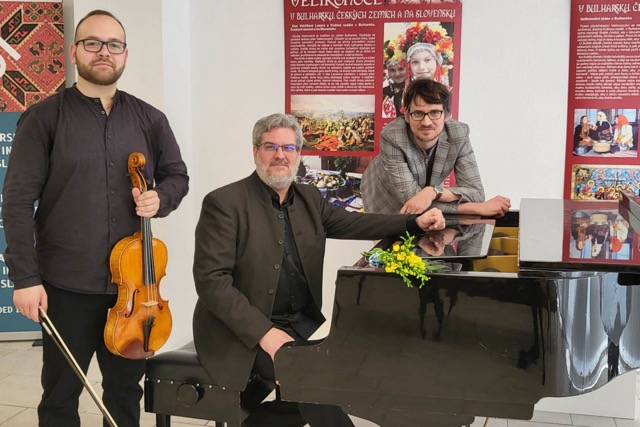 The composition of the group photograph of three people consists of the violist Vojtech Bélu Botoš standing on the left with a viola and the composer and conductor Konstantin Ilievski seated in the centre behind the piano.